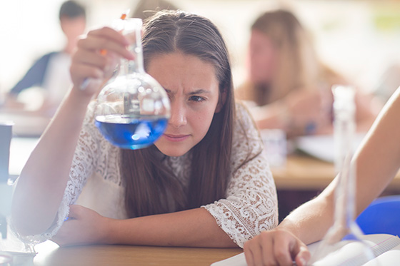 High school girl using a beaker in her chemistry class.