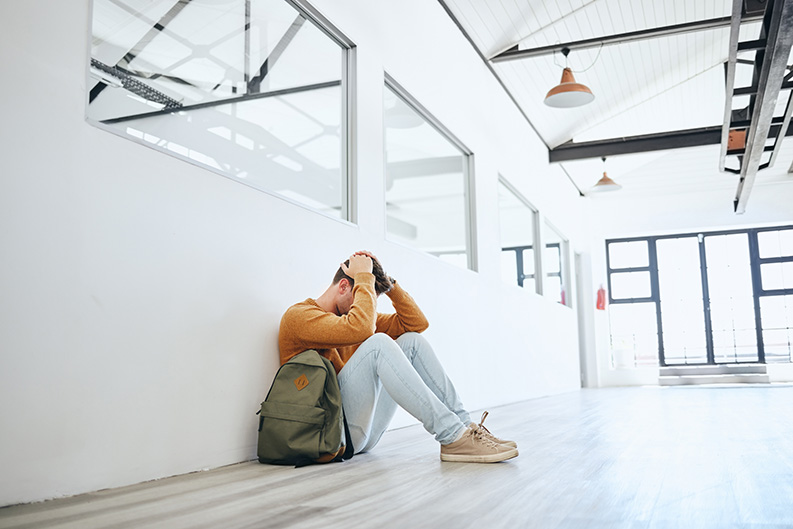 A student with anxiety sitting in a school hallway showing anxious learners struggle with school.