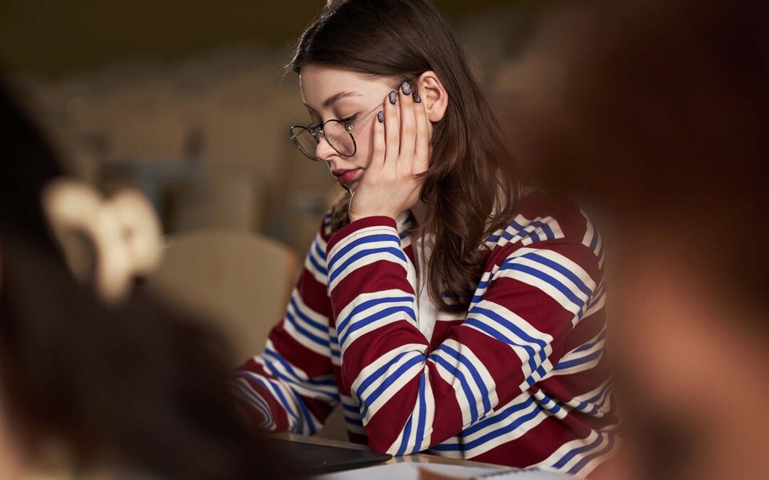 A young student in a classroom looking sad and despondent due to ADHD, anxiety, and burnout.